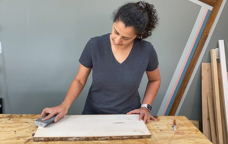 woman sanding a basswood plank with sanding sponge
