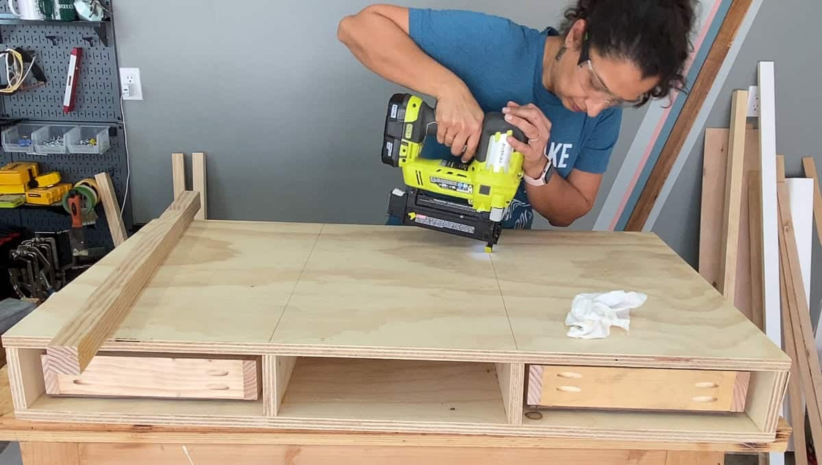 Anika attaching the top of the desk with a nail gun.