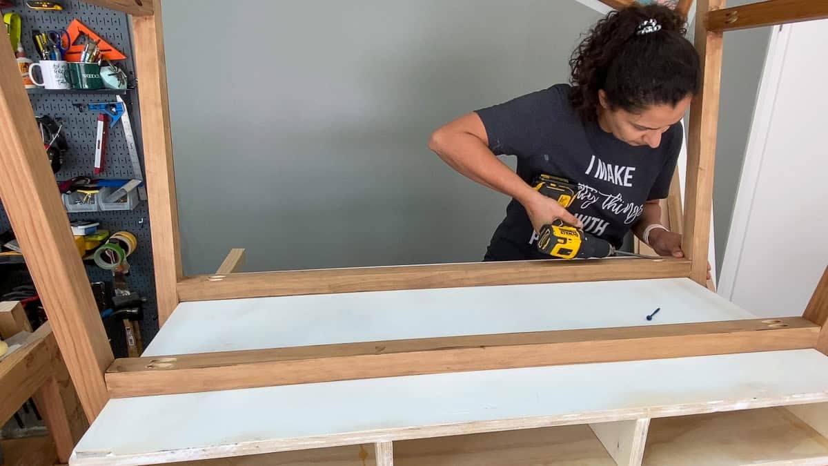 Anika building the leg frame and attaching the boards using a power drill.