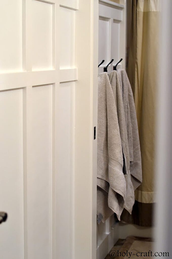 board and batten wall with black hooks in bathroom