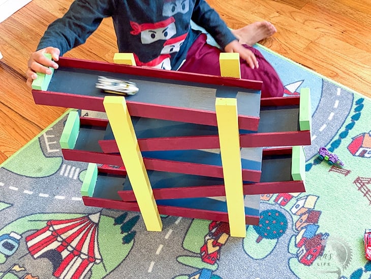Kid pushing car down the DIY wooden race car ramp