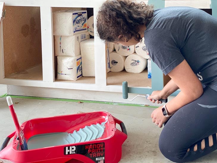 woman rolling paint on the cabinets