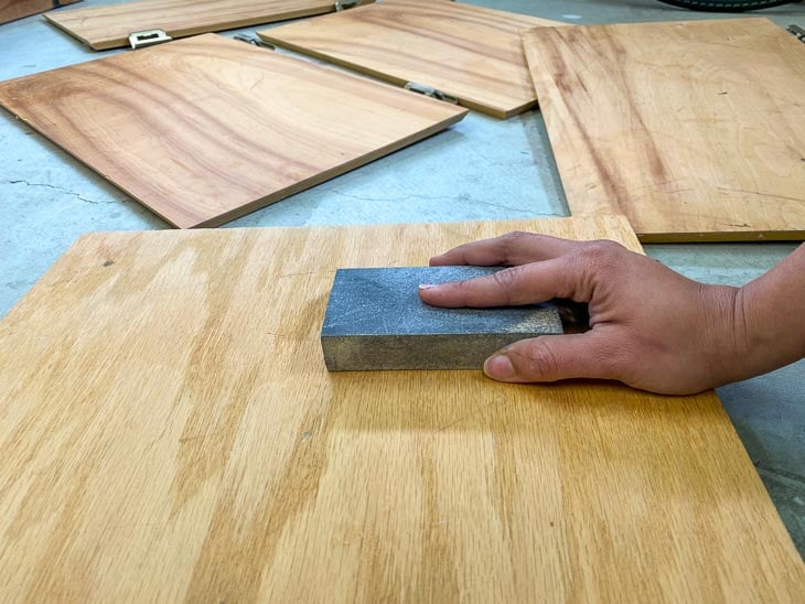 sanding the veneer cabinet with a sanding sponge to prepare for painting
