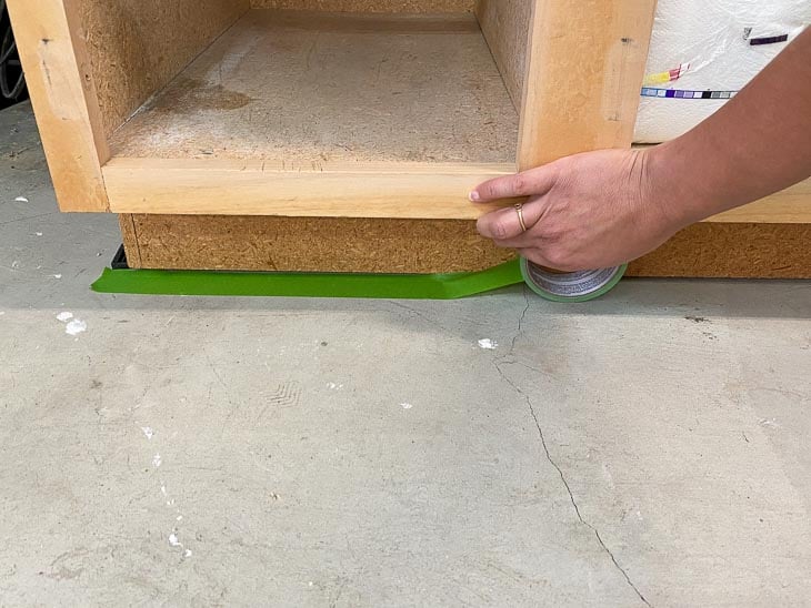setting down masking tape to prep for painting the cabinets