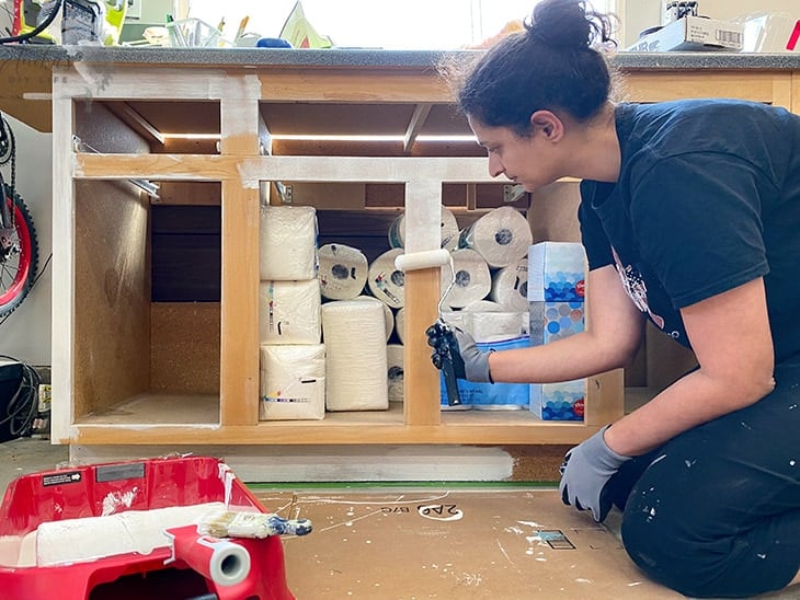 woman rolling paint on the veneer cabinets