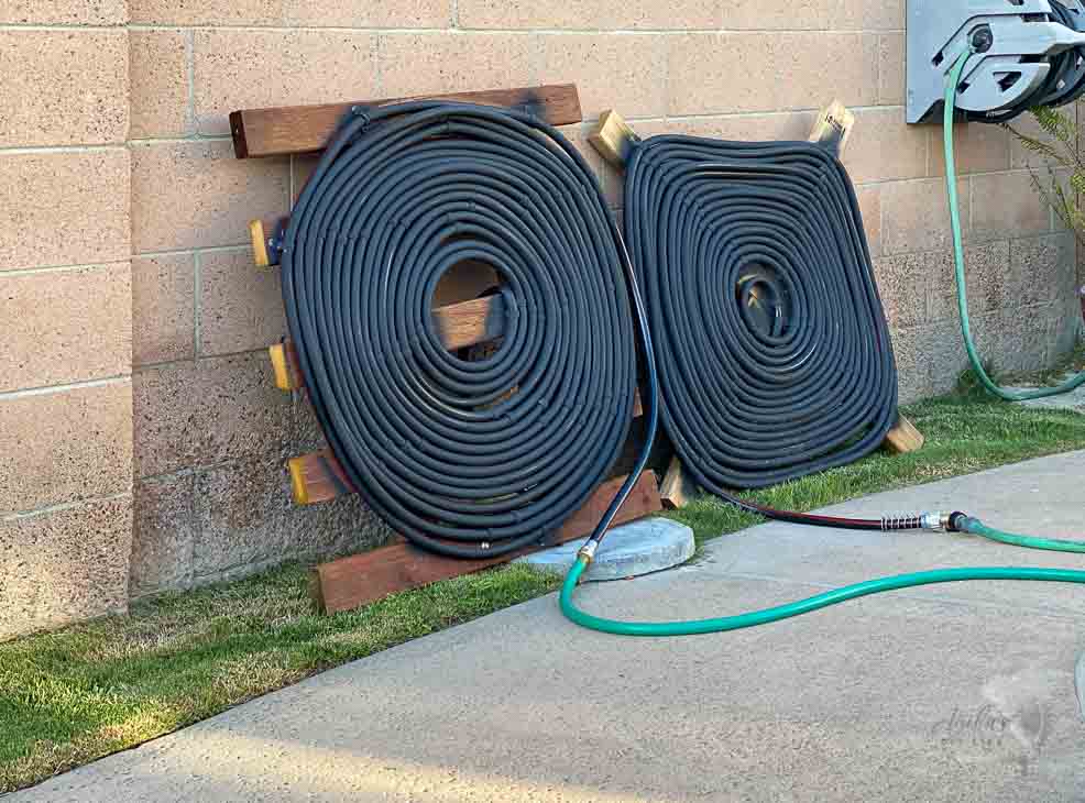 Two homemade solar pool heater coils next to a pool