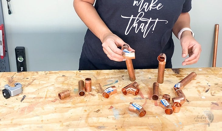 Woman making shapes with copper pipes for lamp