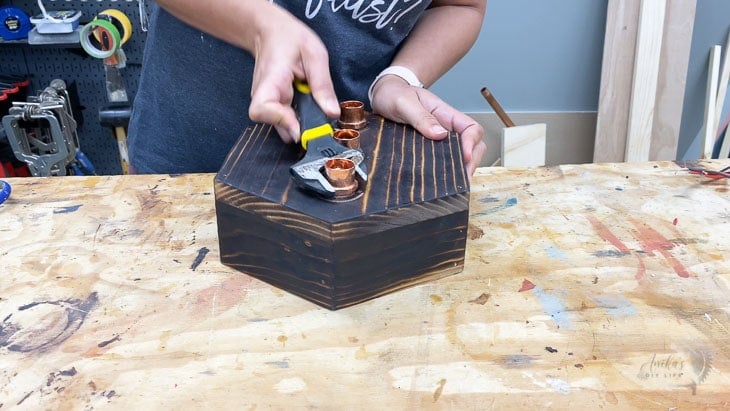 Attaching wopper pipe fitting adapters to wooden base.