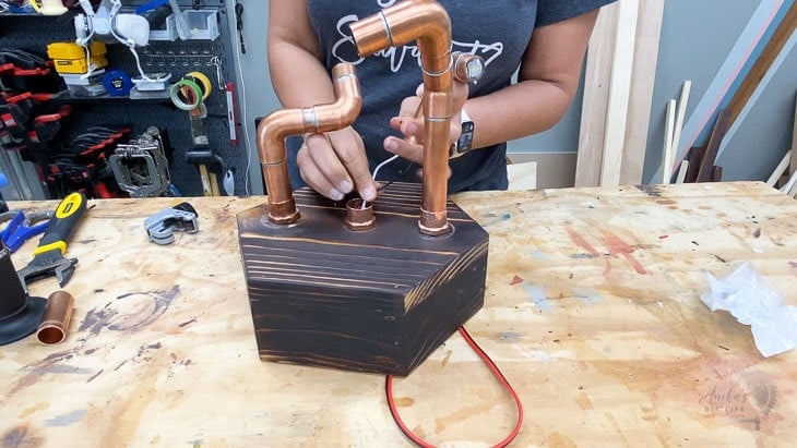 Woman adding the copper pipes to the hexagon bas
