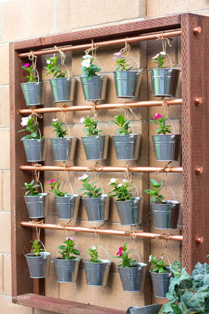 wood and metal hanging garden with twenty small metal buckets with flowers