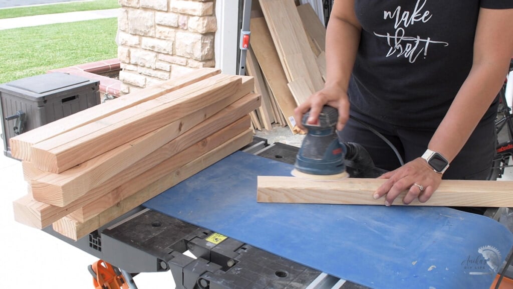 woman sanding wood boards on a blue mat
