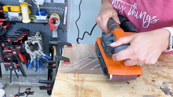 using a belt sander to remove extra metal