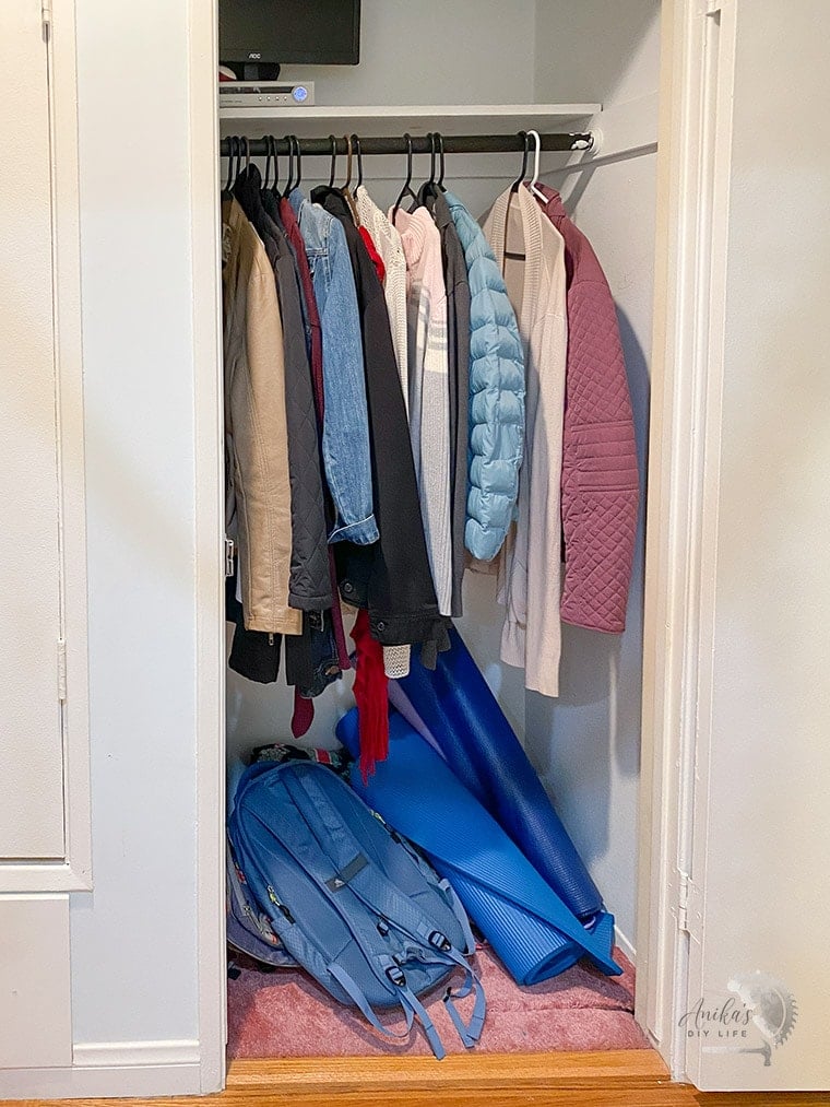 Entryway closet before with coats and pink carpet