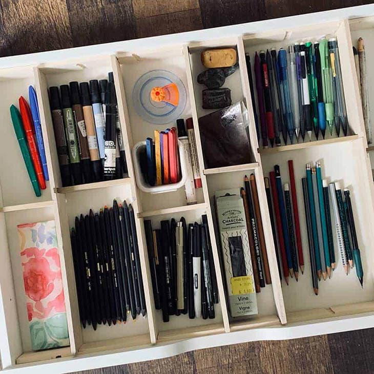 Wooden drawer divider with ten sections filled with office supplies