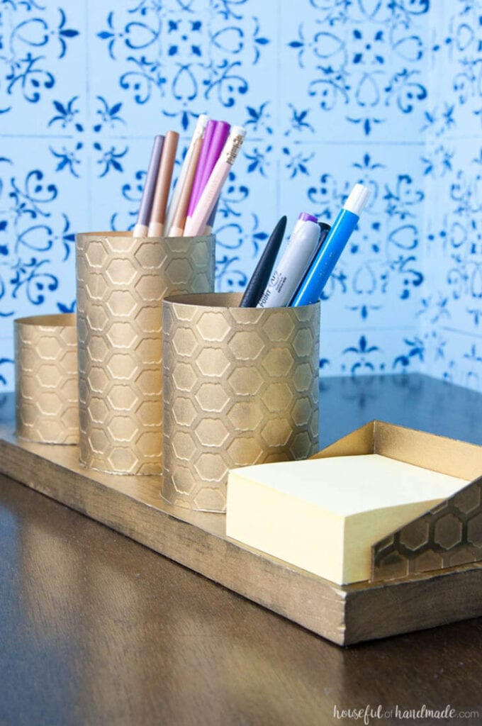Brass colored pencil holders and post it note holder sitting on a desk