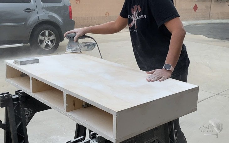 woman sanding plywood to prepare to paint