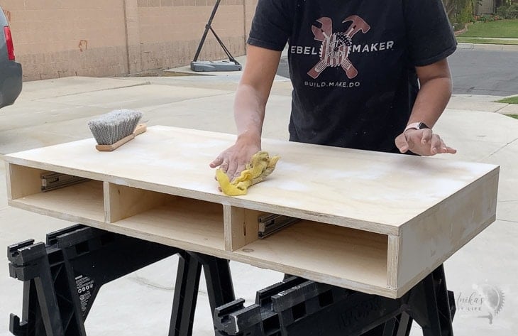 woman wiping off dust from plywood to prepare it for painting