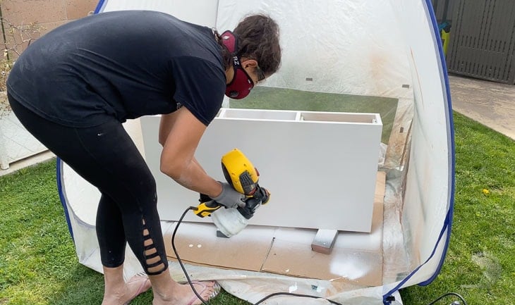 Woman painting the plywood with a paint sprayer