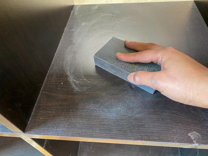 lightly sanding the Ikea Kallax shelf to prepare it for painting