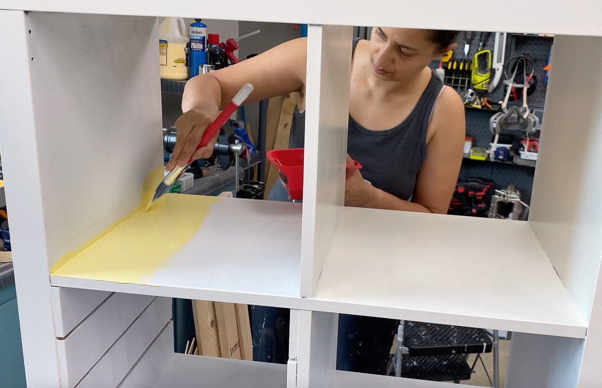 Woman painting the laminate bookshelf