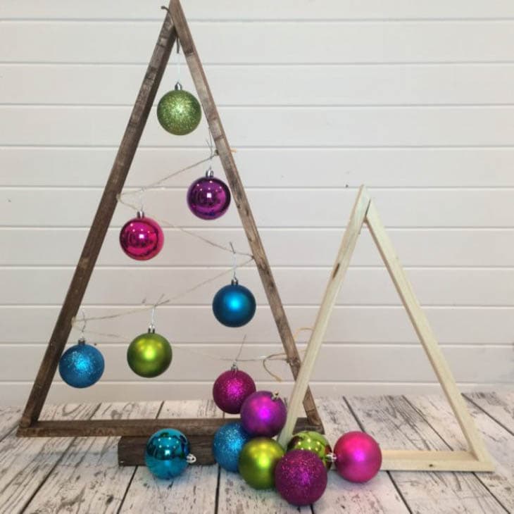 Scrap wood triangles as Christmas trees with colorful ornaments hanging from them