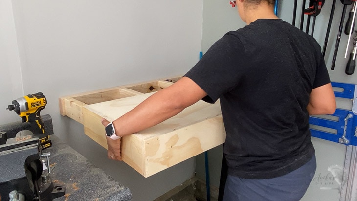 woman sliding floating shelf onto brace on wall