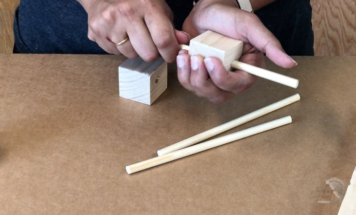 Adding the dowels through the cubes to make the DIY woodland mobile