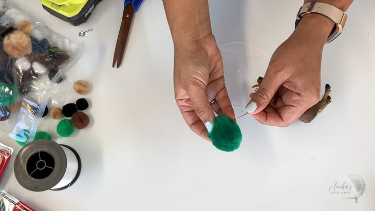 Adding pom poms to the DIY animal theme mobile