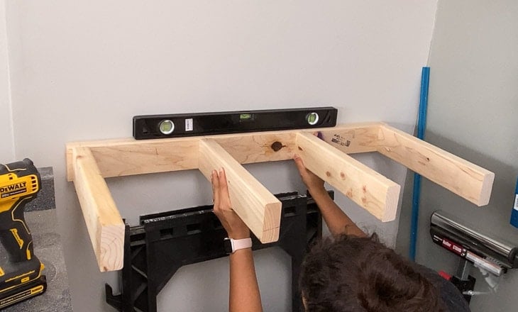 Woman holding up shelf to attach to wall
