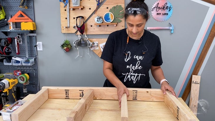 woman putting together 2x4 to build the floating shelf