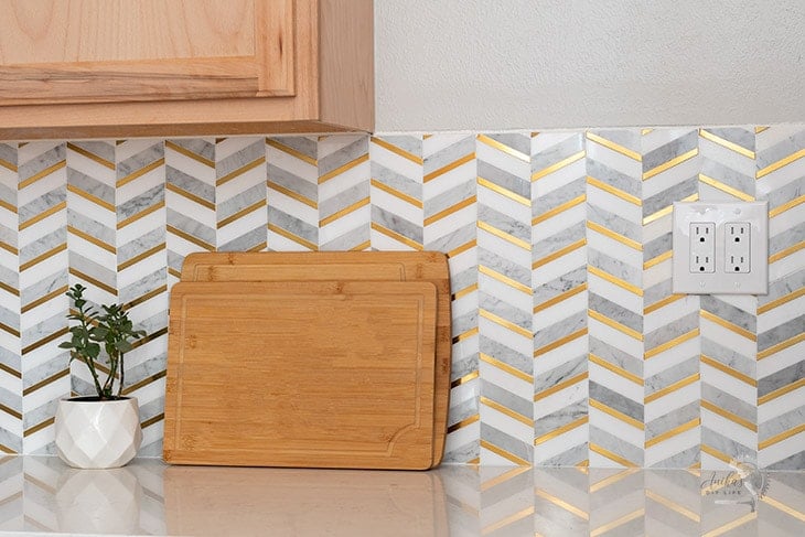 herringbone backsplash tile with gold and marble in the kitchen