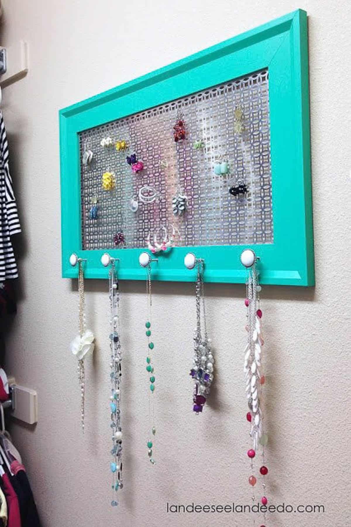 teal painted frame with sheeting and knobs to hold jewelry