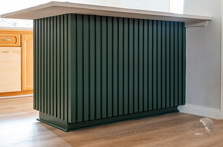Modern slat trim on kitchen island painted dark green