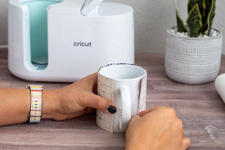 Woman aligning design to mug to use in the Cricut MugPress