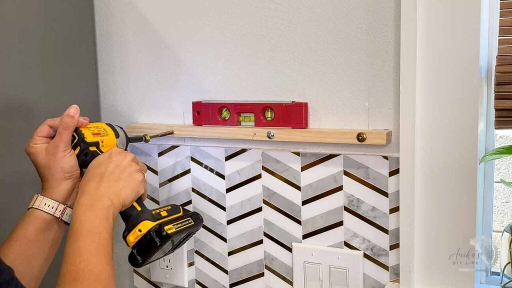 woman using structureal screws to attach board to wall.