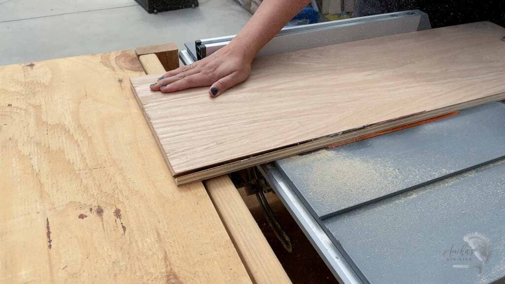 Woman cutting plywood on table saw to build kitchen shelves