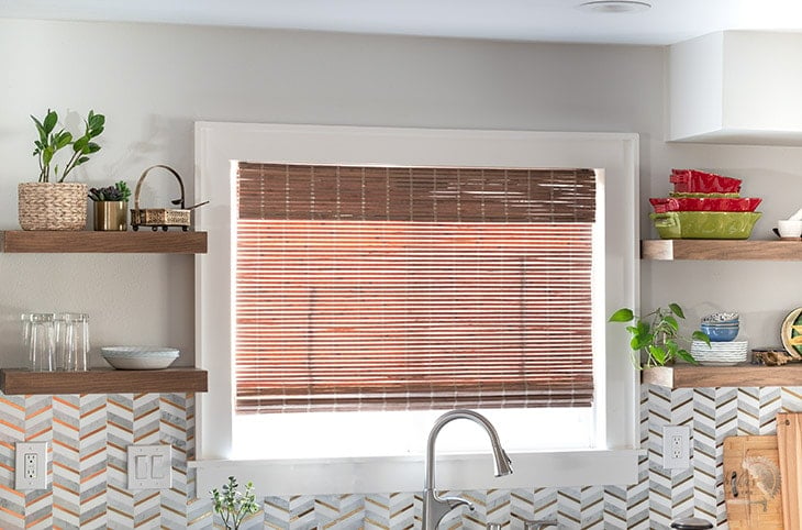 DIY wood floating shelves on both sides of a window in a kitchen