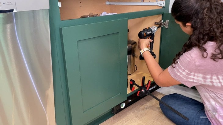 Woman installing kitchen cabinet doors