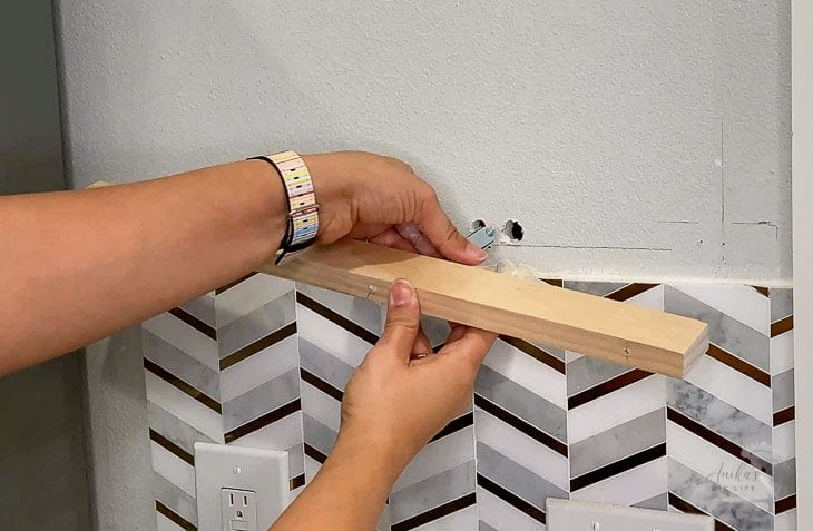 Woman inserting toggle bolt into wall to install