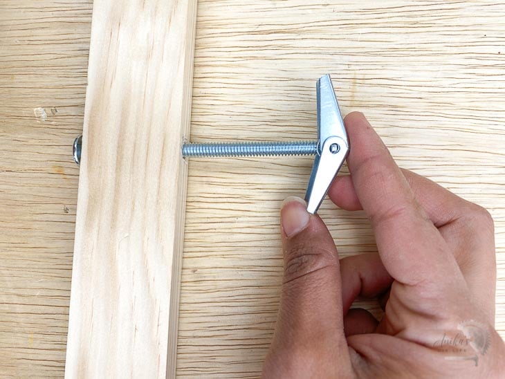 Woman threading toggle onto bolt to attach board to wall