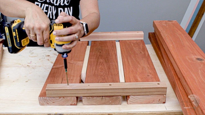 woman building the short side by attaching 2x2 rails