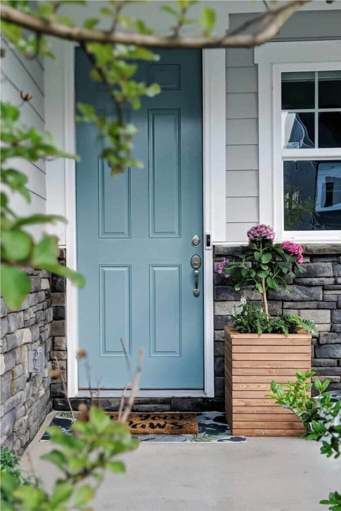 Wood planter box on front porch with blue front doof