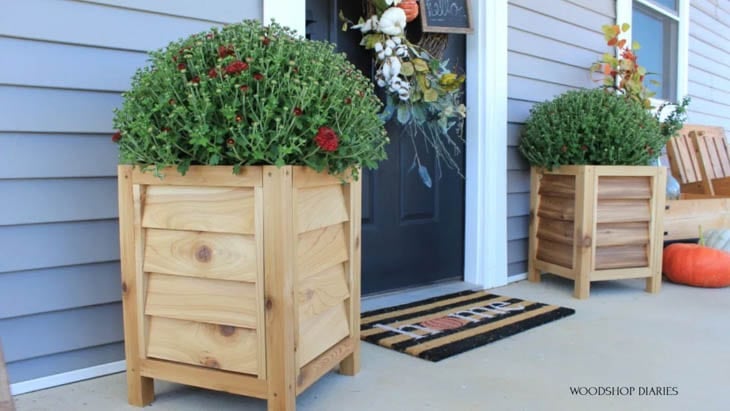 2 DIY wood planter boxes in porch with mums in them