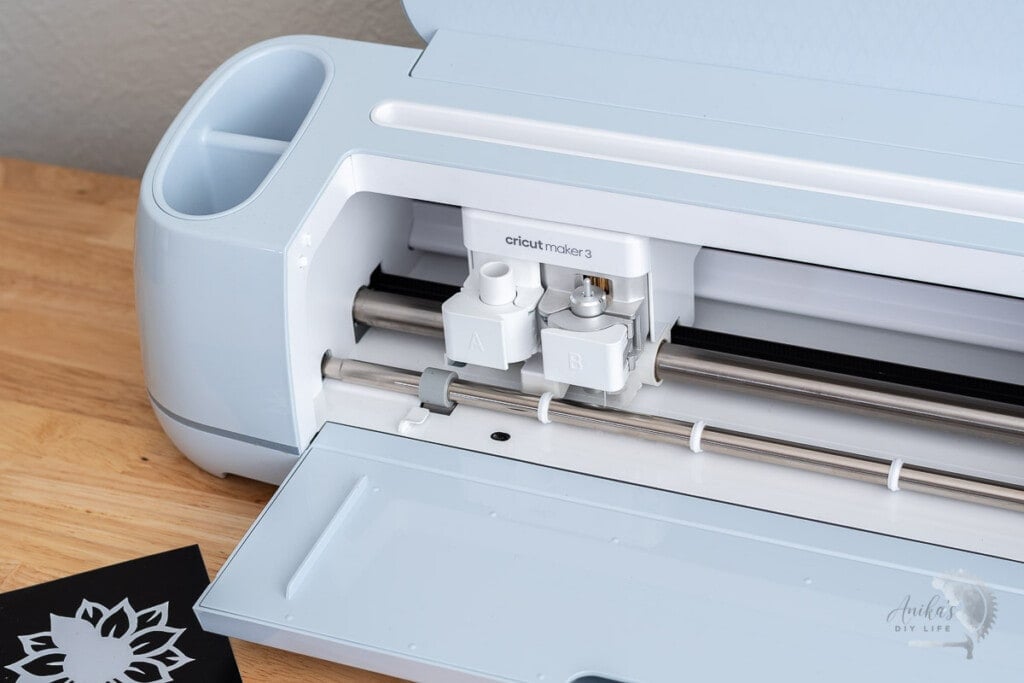 Cricut maker 3 open on a table with cut vinyl