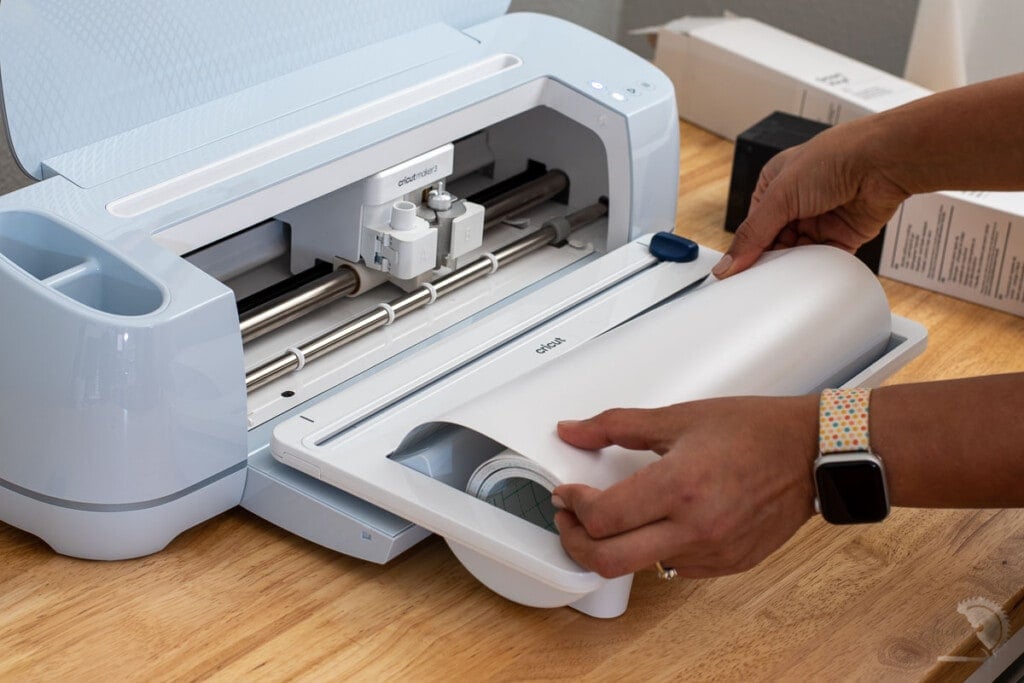 Woman loading vinyl roll into the Cricut roll holder for Cricut Maker 3