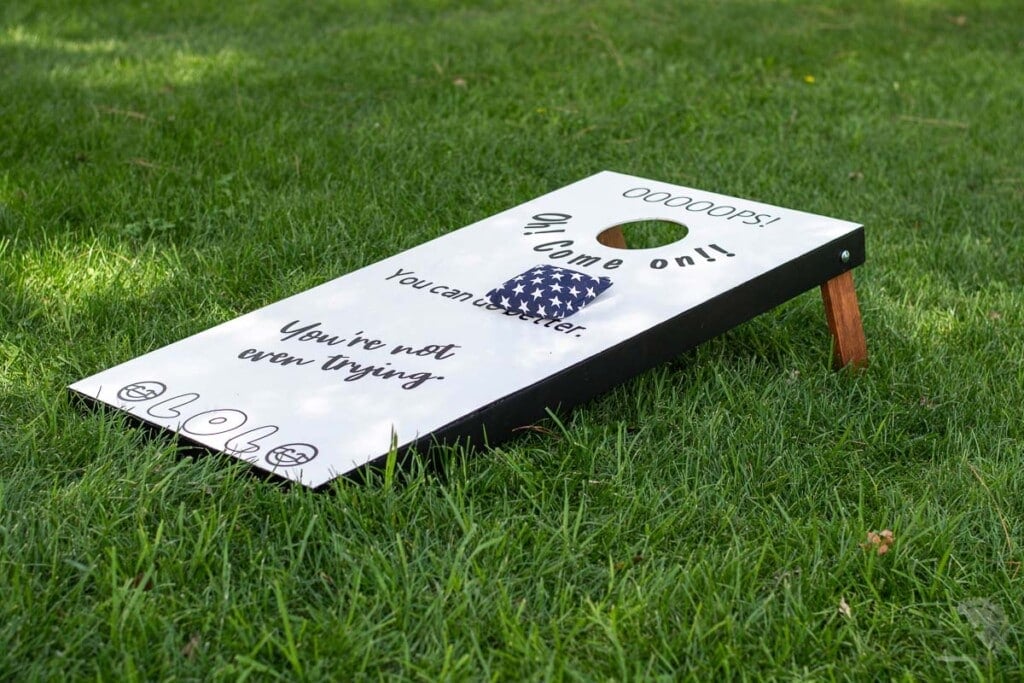 white cornhole board in the grass
