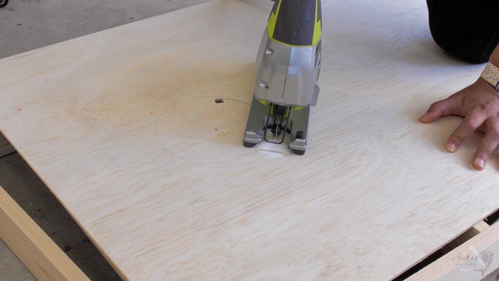 Woman cutting hole in board using a jigsaw