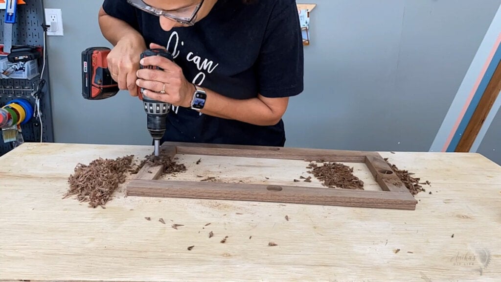 woamn drilling holes into the walnut frame using a Forstener bit