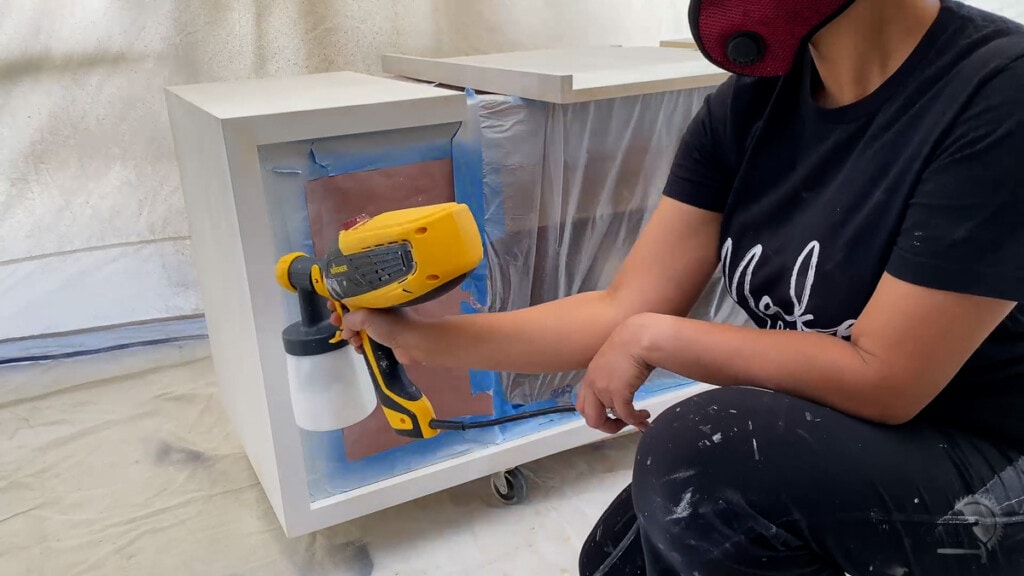 painting the exterior of the console table white with a paint sprayer