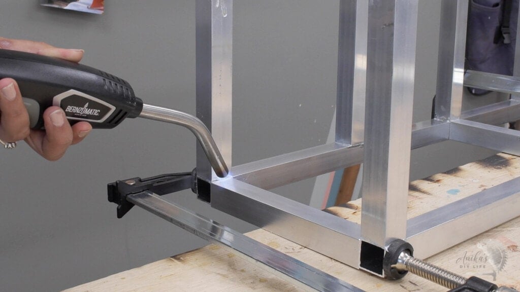 Woman brazing aluminum tubes to build a metal plant stand